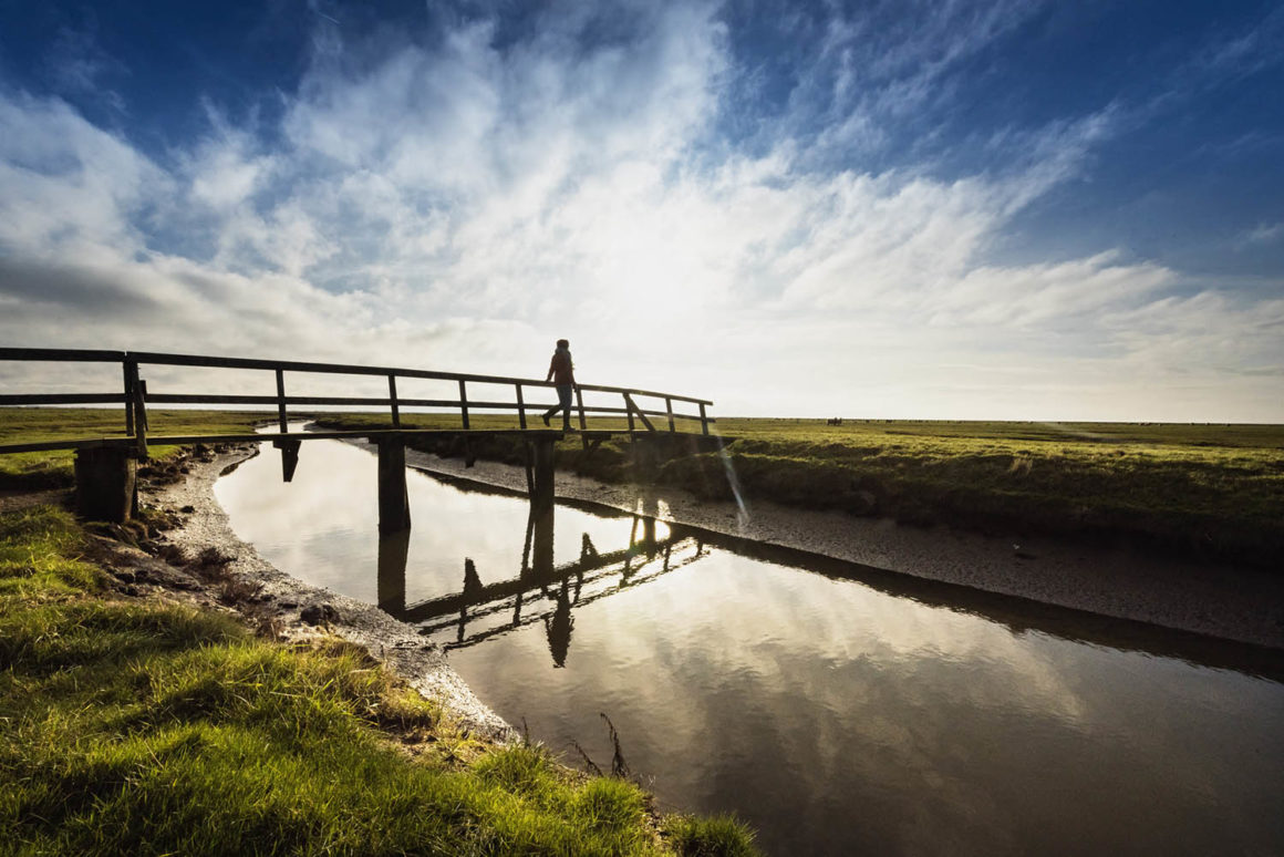 Nordsee. Winter-Abenteuer 8 Wanderer ueberquert Priel auf der Hallig Nordstrandischmoor